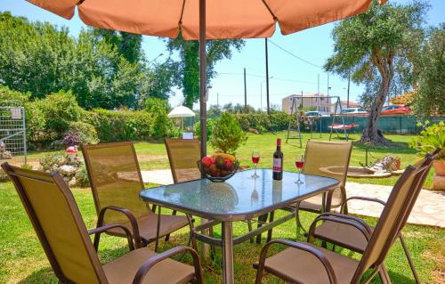 罗达Noufris House Roda Corfu的院子里伞下的桌子和椅子