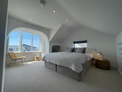 马根波思Baywatch Mawgan Porth Spacious Home sleeps 9, Games room, Parking & Garden的白色卧室配有床和椅子