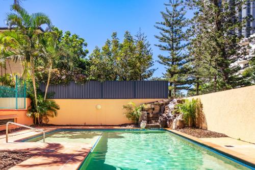 黄金海岸阿鲁巴金沙度假酒店的一座树木繁茂的建筑前的游泳池