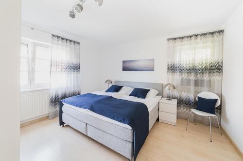 农嫩霍恩Ferienwohnung im Fischerhaus的白色卧室配有蓝色的床和椅子