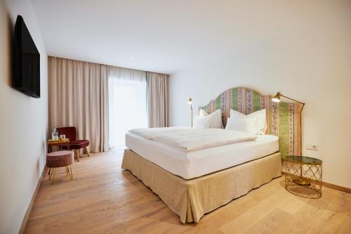 格蒙登Boutiquehotel Zum Goldenen Hirschen的酒店客房设有一张大床和一台电视。