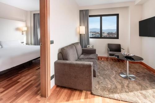 格拉纳达B&B HOTEL Granada Estación的酒店客房设有一张沙发和一张床