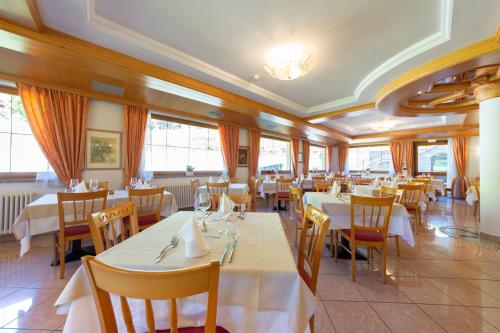 莫埃纳Flos Hotel的餐厅设有白色的桌椅和窗户。