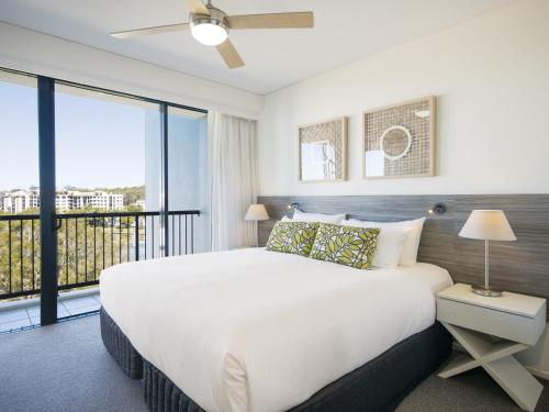 亚历山德拉岬角Oaks Sunshine Coast Seaforth Resort的一间带一张白色大床的卧室和一个阳台