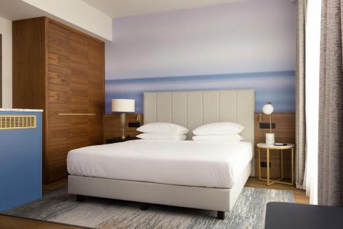尼斯Sheraton Nice Airport的卧室配有白色的床和蓝色的墙壁