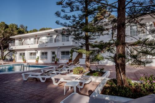 米乔尔海滩Hostal Es Pi - Emar Hotels的一座带游泳池和桌子的度假村和一座建筑