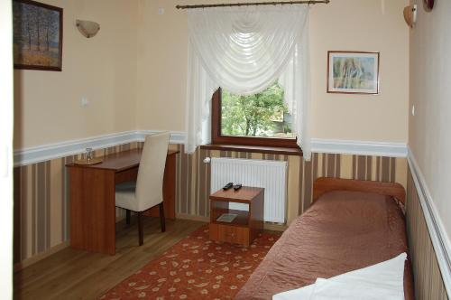 尼萨瑞多斯餐厅酒店的一间卧室配有一张床、一张书桌和一个窗户。