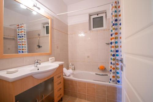 Áyios DhimítriosDimitrios Apartment的一间带水槽、浴缸和镜子的浴室