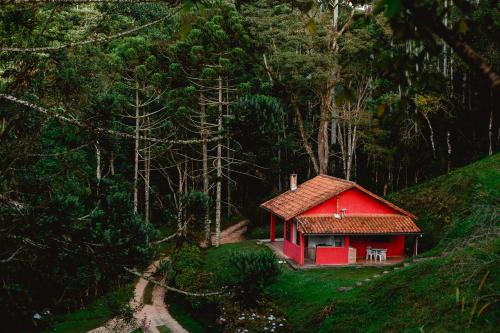 康塞高伊比蒂波卡Sítio das Hortênsias Chalés的森林中间的一座红色小房子
