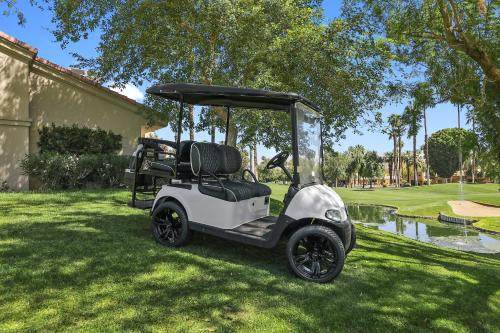 棕榈荒漠Palm Valley Full Access to Golf, Tennis, and Pickle Ball- Luxury 3 King Beds 3 Full Baths的停在草地上的高尔夫球车