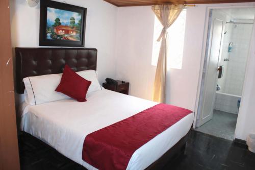 波哥大Casa Hotel Victoria的一间卧室配有一张大床、红色毯子和窗户。