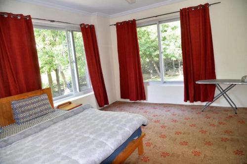 锡卡都Fort and Indus River View Guest House的一间卧室配有红色窗帘、一张床和一张桌子