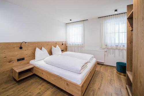 圣坎迪朵Kuenz Dolomites App 5的一间卧室配有一张带白色床单的大床