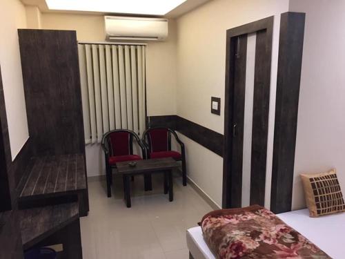 西里古里Atithi Guest House的一间设有两把椅子、一张床和钢琴的房间