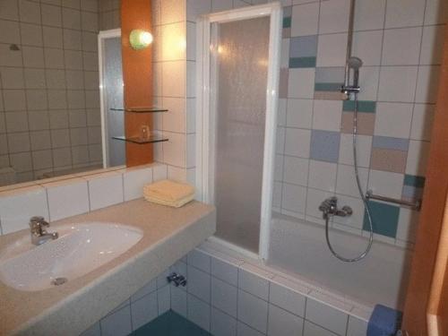 Nötsch马尔科酒店的带淋浴、盥洗盆和浴缸的浴室