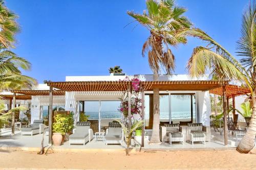 萨尔雷Villa Cristina Alojamento, Praia de Chaves, Boa Vista, Cape Verde, WI-FI的海滩上拥有白色椅子和棕榈树的度假胜地