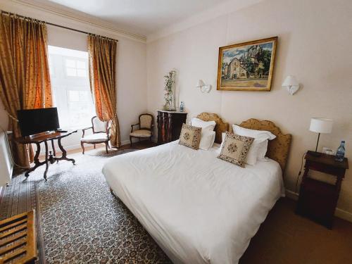 拉马莱恩Hôtel-Restaurant Le Manoir De Montesquiou的卧室配有一张白色大床和一张书桌