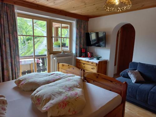 罗孚尔Ferienzimmer Brennerbauer的一间卧室配有一张床、一张沙发和一个窗口