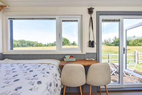滑铁卢维尔Crabden Shepherd Hut - Blendworth的一间卧室配有一张床、两把椅子和窗户
