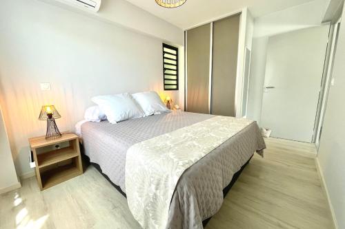 帕皮提Mereani flat brand new condo in the center of Papeete的一间卧室配有一张床和一张带台灯的桌子