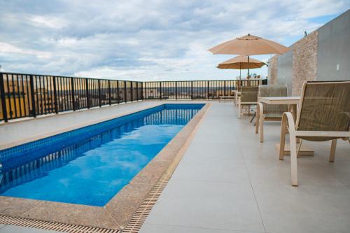 巴西利亚诺比尔纪念套房酒店的阳台的游泳池配有椅子和遮阳伞