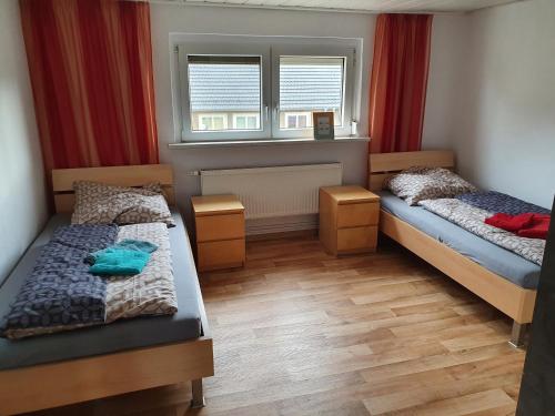 巴特利本韦达HässelHof - 80qm Ferienwohnung im Zentrum von Bad Liebenwerda的一间卧室设有两张床,窗户配有红色窗帘