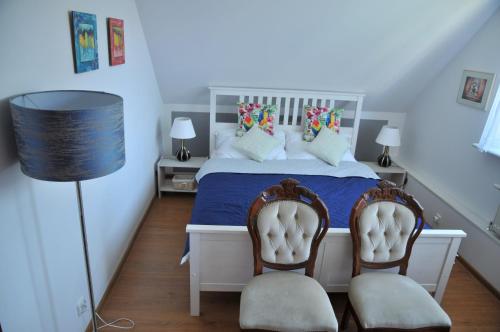 格丁尼亚Apartament pod limbą的卧室配有白色的床和两把椅子