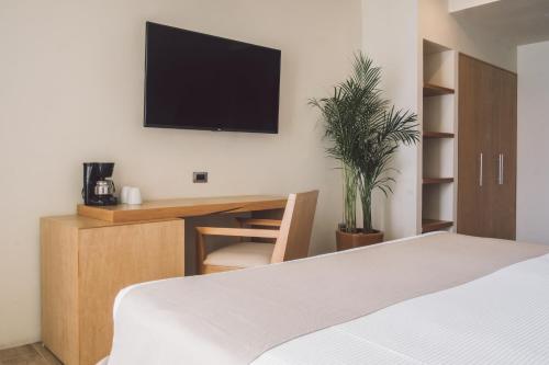 坎昆坎昆NYX酒店的一间卧室配有一张床和一张桌子,墙上配有电视