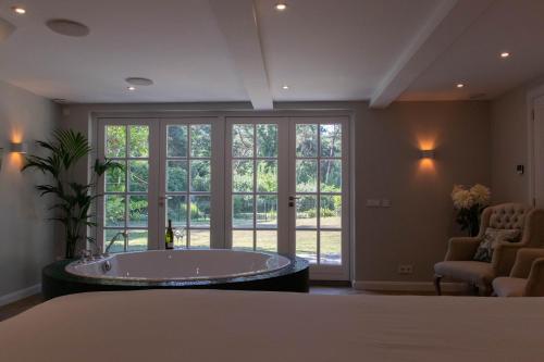 蒂尔堡Guesthouse "Mirabelle" met indoor jacuzzi, sauna & airco的大型客房,窗户前设有浴缸