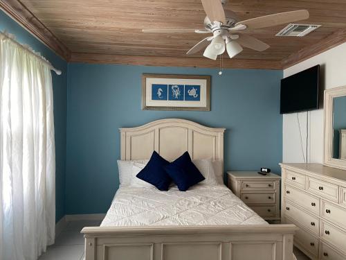 乔治镇蓝宝石花园排屋别墅的一间卧室配有一张蓝色墙壁的床和吊扇