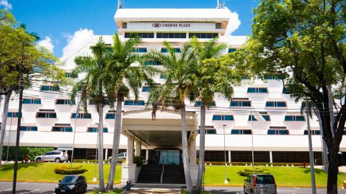 马那瓜马那瓜皇冠广场酒店的一座白色的建筑,前面有棕榈树