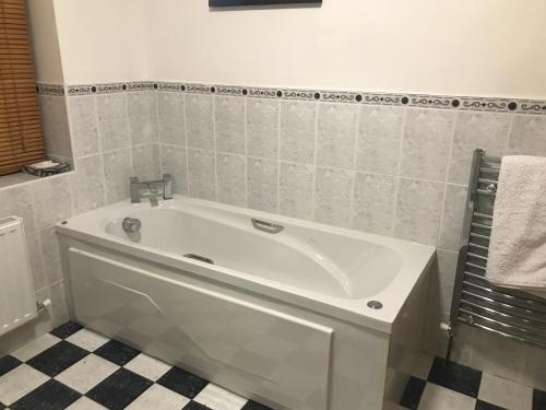肯梅尔Lissyclearig Lodge的浴室铺有瓷砖地板,配有白色浴缸。
