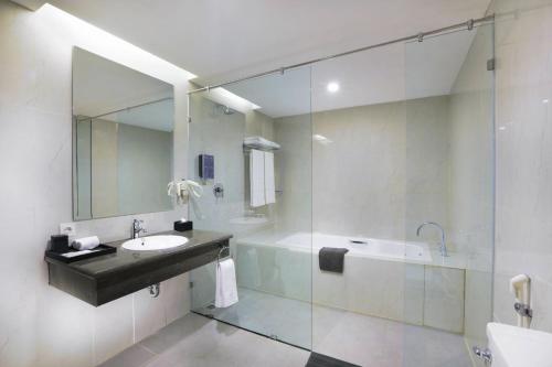马卡萨Harper Perintis by ASTON的一间带水槽、浴缸和镜子的浴室