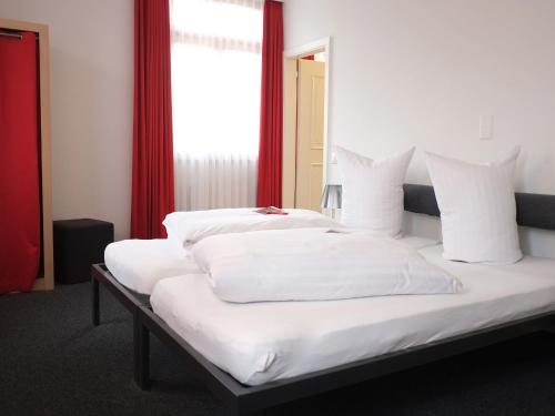 阿尔邦布劳雷弗洛辛酒店的一间卧室设有两张带白色床单的床和窗户。