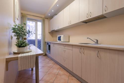维尔纽斯马拉酒店的厨房配有白色橱柜和植物桌子