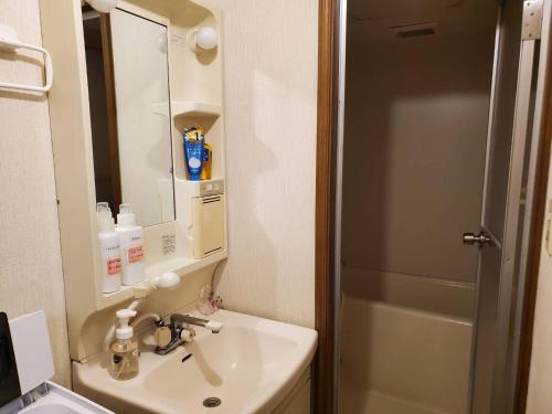 神户petit room201三宮10mim的一间带水槽和镜子的浴室以及一台冰箱