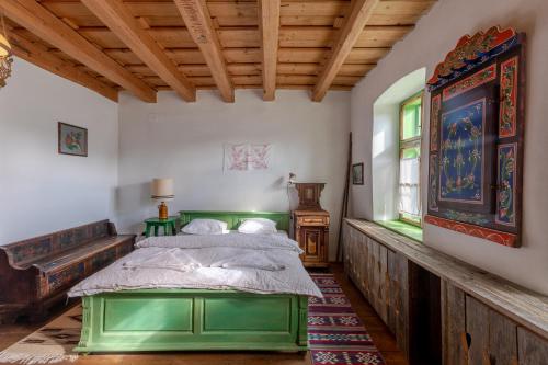 维斯克里Viscri 32 - White Barn and Blue House的一间带绿色床的卧室,位于带木制天花板的房间内
