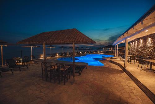 巴特斯欧Blue Bay Resort Village的一个带桌椅的庭院和一个夜间游泳池