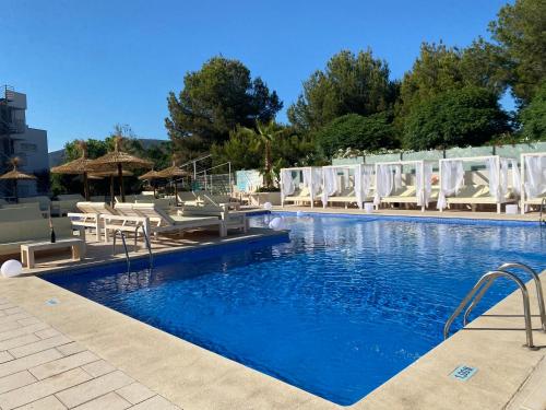 马盖鲁夫INN Mallorca Aparthotel的一个带白色椅子的游泳池,一个度假村