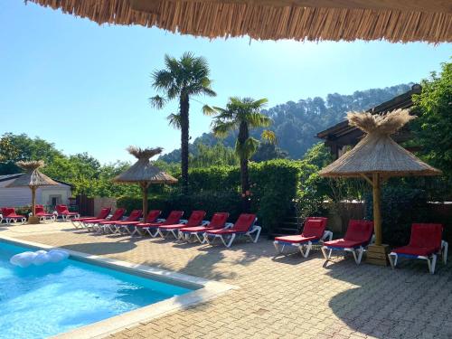 RibesHameau du Prat的毗邻度假酒店的带椅子和遮阳伞的游泳池