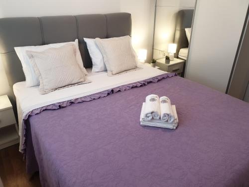 斯普利特Lavanda 2的一间卧室配有一张紫色床和2双拖鞋