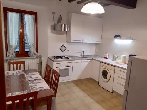 芬奇La casa di Elisa的厨房配有白色橱柜、桌子、桌子和水槽。