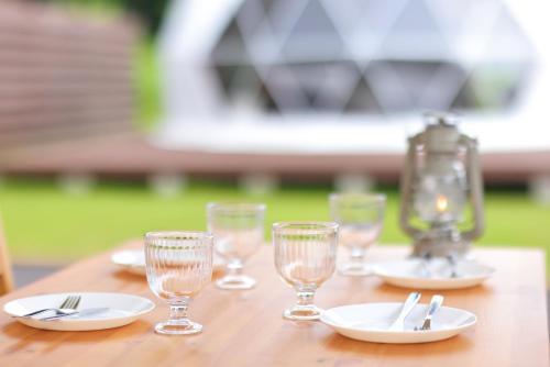 富士河口湖Glamping Resort Varie的一张木桌,上面有盘子和玻璃杯