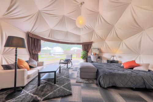 富士河口湖Glamping Resort Varie的一间卧室配有一个带一张床和一张沙发的帐篷