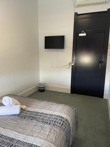 古尔本Tattersalls Hotel的卧室配有一张床,墙上配有电视。