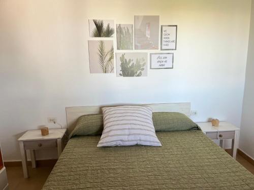 卡兰博希Villa Calma的卧室配有一张带两张桌子的床,墙上挂有图片