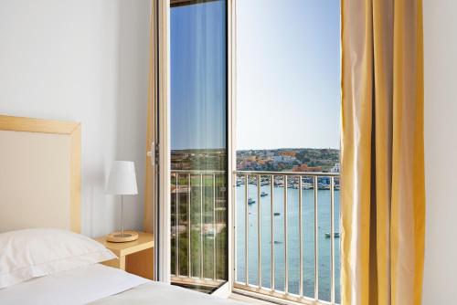兰佩杜萨Hotel Vega的一间卧室设有大窗户,享有水景