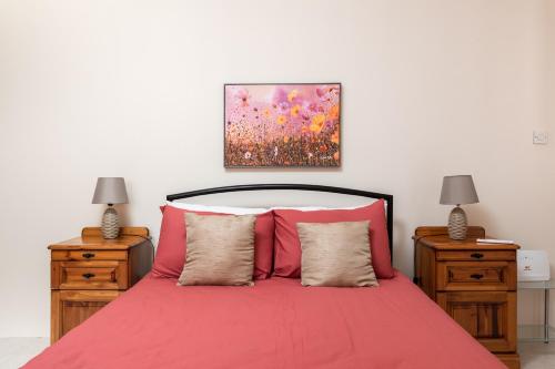 姆西达Spacious, Bright & Cosy 2 Bedroom 2 Bathroom Apartment - Msida Uni Heights的一间卧室配有红色的床和2个床头柜