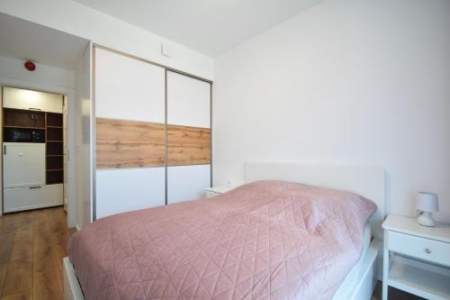 洛格沃Apartament Rogowo的一间卧室配有一张带粉红色棉被的床