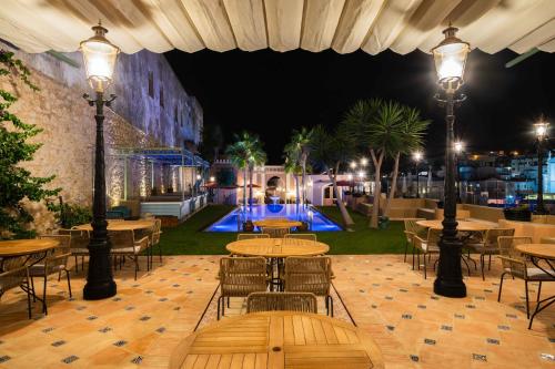 阿尔布费拉Vila Origens Boutique Hotel Albufeira – Adults Only的一个带桌椅的庭院和一个夜间游泳池